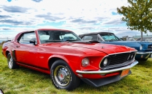 Ярко-красный Ford Mustang красуется на зеленой траве